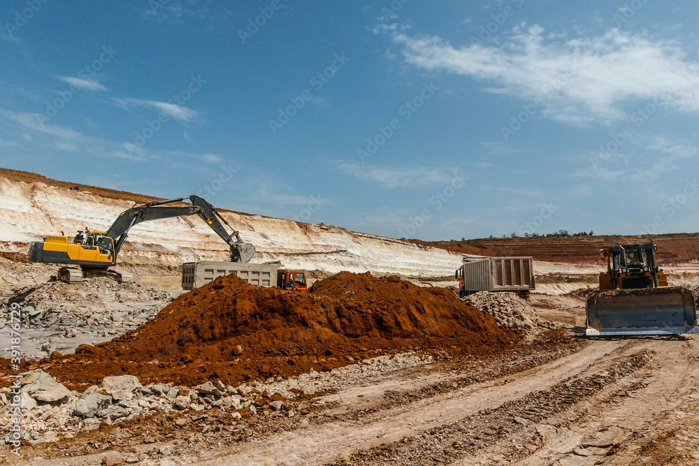 yellow excavator mines blue clay and loads into grey truck. Clay mining. yellow excavator mines blue clay and loads into grey truck. Clay mining.