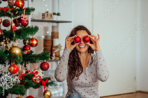 Schilderij op canvas Happy woman having fun at home while decorating Christmas tree