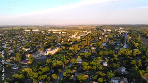 Aerial drone shot of Donduseni city with multiple residential buildings and greenery and fields. Sunset in Moldova photo