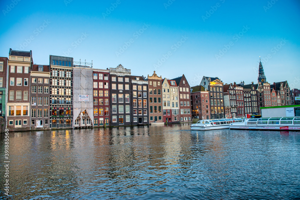 AMSTERDAM, THE NETHERLANDS - APRIL 25, 2015: Traditional houses and buildings on the canal with boats on the water