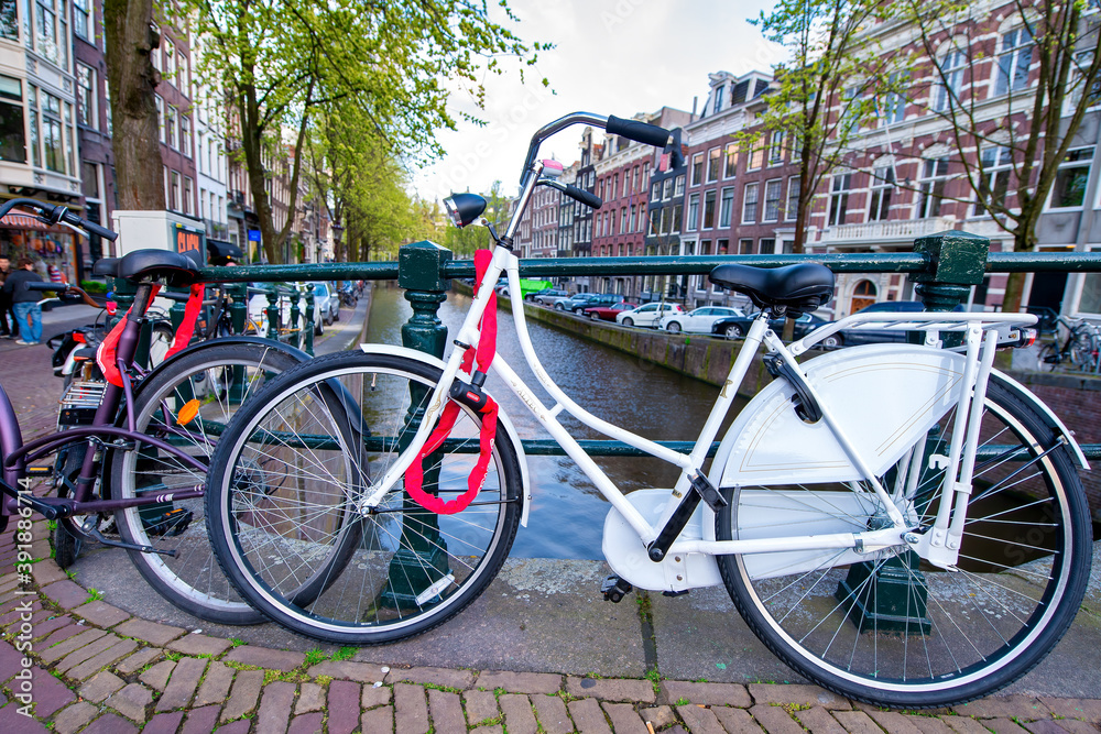 AMSTERDAM, THE NETHERLANDS - APRIL 25, 2015: The life of canals and streets. Bikes parked along the bridge
