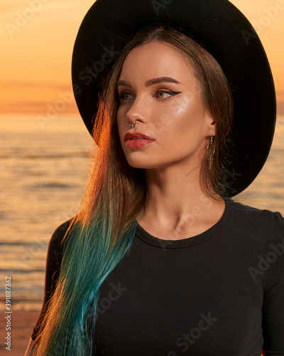 Woman with green hair and in black clouths on a beach on sunset.
