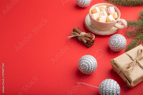 Christmas or New Year composition. Decorations, silver balls, fir and spruce branches, cup of coffee, on a red background. Side view, copy space.