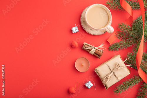 Christmas or New Year composition. Decorations, box, fir and spruce branches, cup of coffee, on a red background. Top view, copy space.
