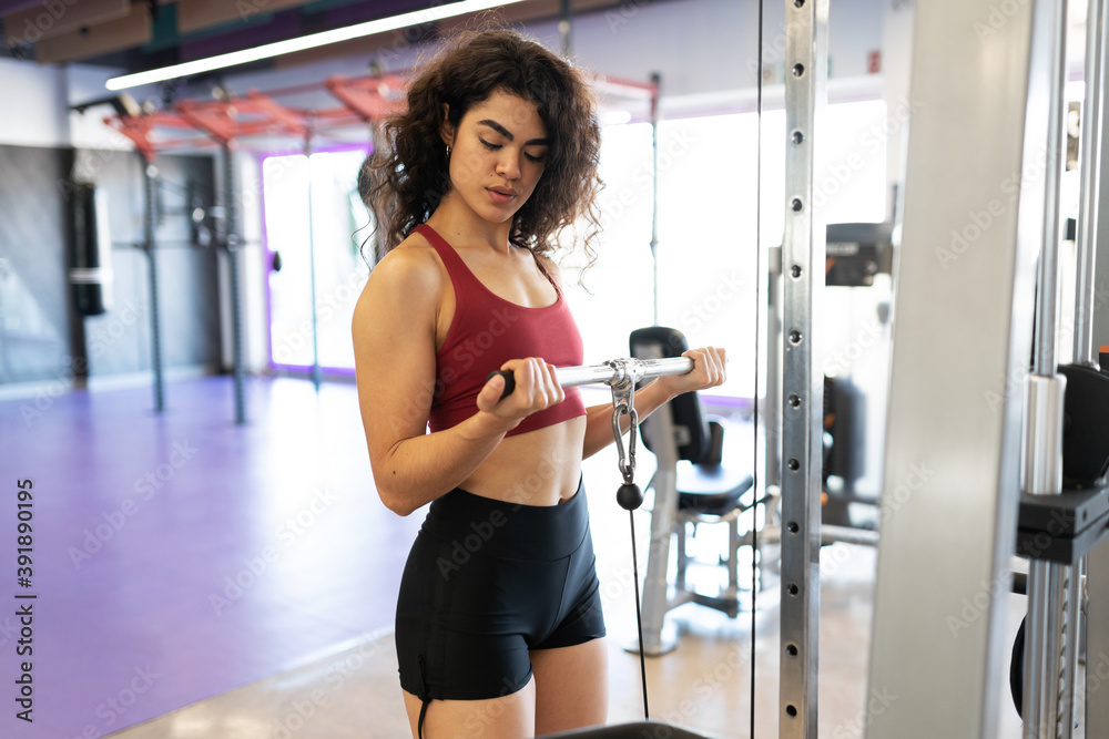 Attractive woman using the gym cable machine Attractive woman using the gym cable machine