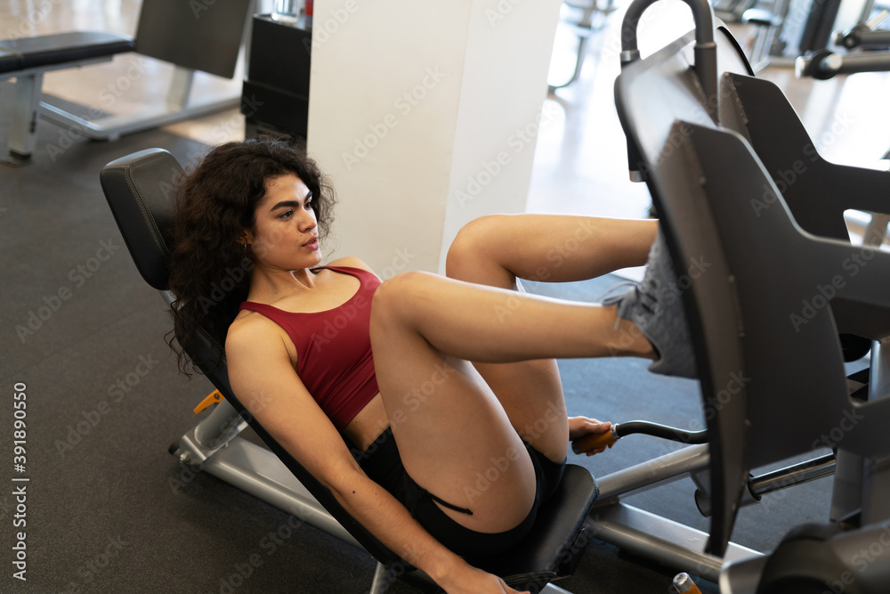 Fit woman working out her quadriceps with a gym machine