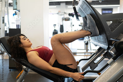 Woman in her 20s exercsing with a leg press machine