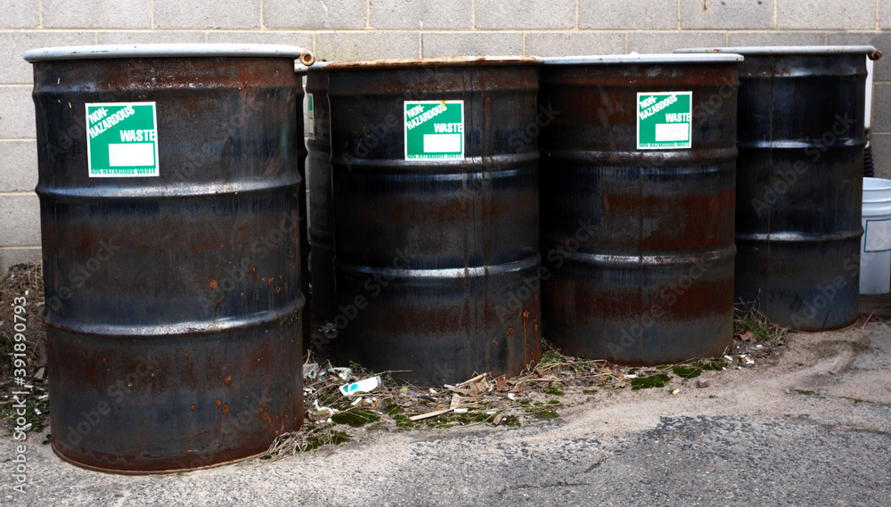 Row of sealed metal barrels labeled NON HAZARDOUS WASTE. Row of sealed metal barrels labeled NON HAZARDOUS WASTE.