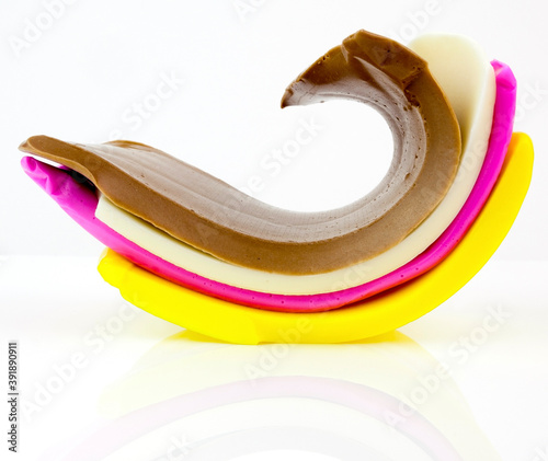 Elastic ribbons of colorful candy taffy on a reflective surface.