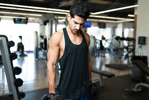 Good looking man holding two weights at the gym