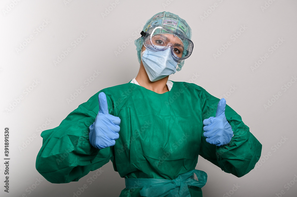 Enfermera protegida con traje (EPI), gafas y mascarilla, tiene los dos pulgares arriba Enfermera protegida con traje (EPI), gafas y mascarilla, tiene los dos pulgares arriba