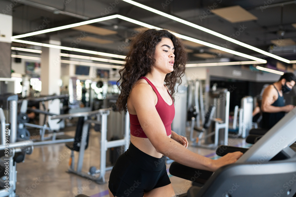 Young woman preparing her workout on the electronic treadmill