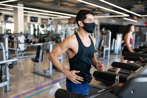 Muscular fit hispanic man exercising in a machine at the gym