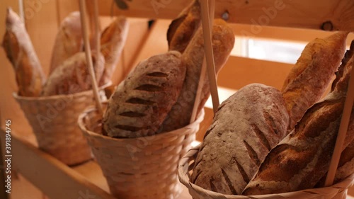 Breads and baked goods large assortment in decorative baskets on wooden bakery shelves in background slow motion medium shot in 4K