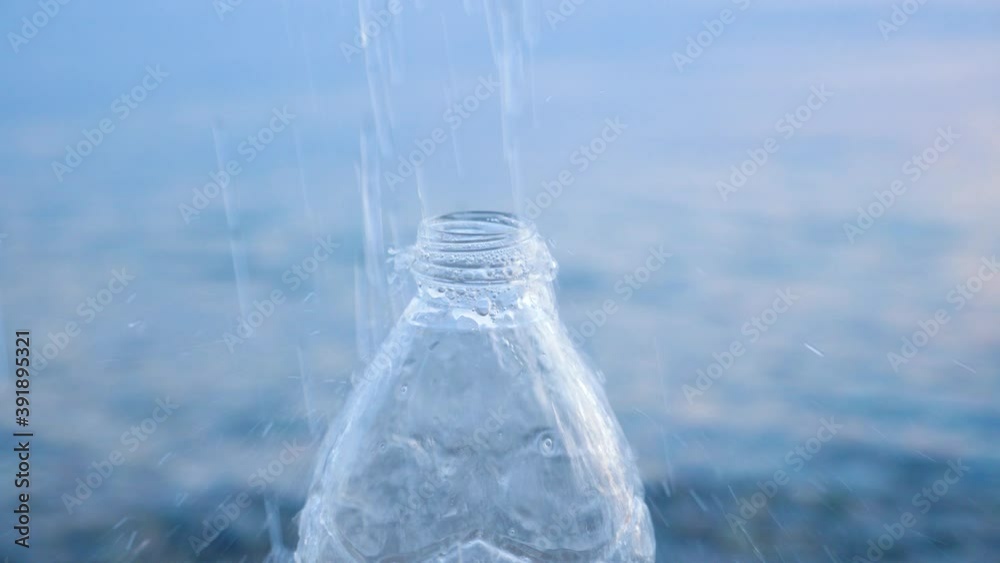 Natural Drinking Purity Water. Waterdrops Falling on an PET Bottle. Beautiful Drops of Water Poured into a Empty Transparent Plastic Bottle Filling with Fresh Cool Water on Blue Water Background. Sea Natural Drinking Purity Water. Waterdrops Falling on an PET Bottle. Beautiful Drops of Water Poured into a Empty Transparent Plastic Bottle Filling with Fresh Cool Water on Blue Water Background. Sea