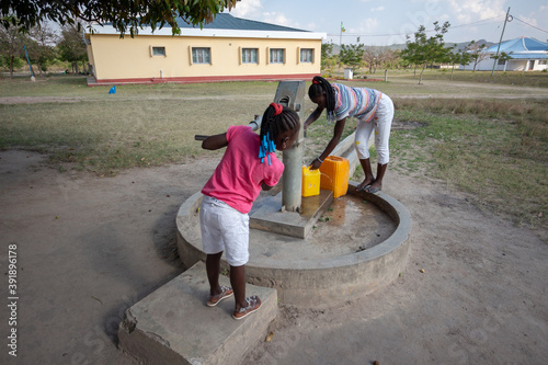 Young girls getting fresh water in the community hand water pump in rural Africa