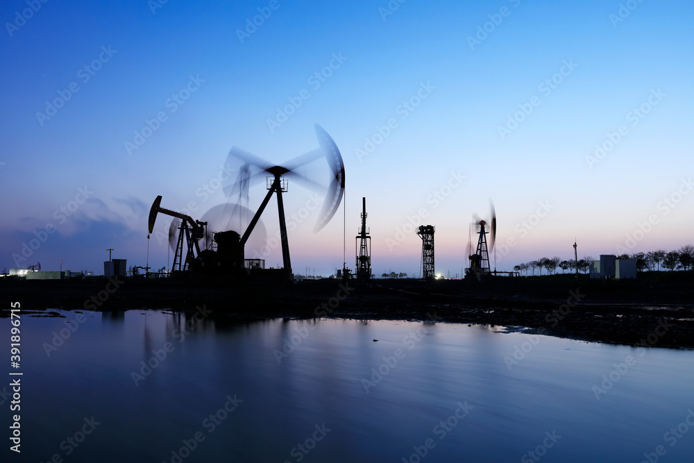 Fototapeta premium the oil pump in the evening, the evening silhouette of the pumping unit, the silhouette of the oil pump