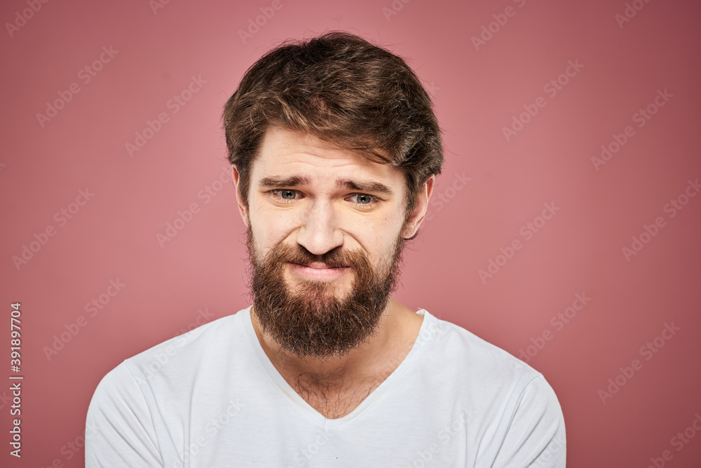Emotional bearded man in white T-shirt discontent pink background Emotional bearded man in white T-shirt discontent pink background