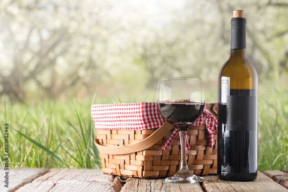 Elegant bottle of red wine and wine glass on picnic basket background. Backstage of romantic picnic at the garden. Elegant bottle of red wine and wine glass on picnic basket background. Backstage of romantic picnic at the garden.