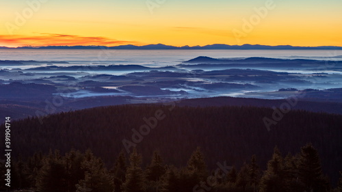 Inversion in the valley during sunrise with mountain ridge in the background.