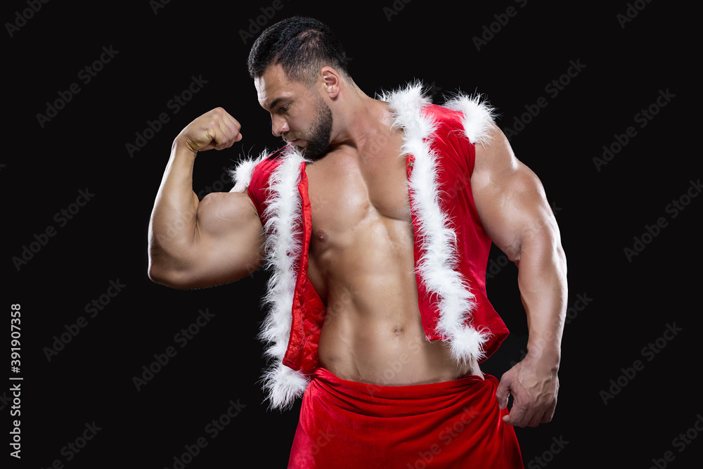 Nublado estar principio Young sexy Santa Claus in a red carnival costume on a naked body shows off  his strong biceps isolated on black background foto de Stock | Adobe Stock