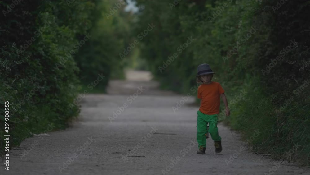 Funny little child with hat holding a lamp walking on empty rural road, night Funny little child with hat holding a lamp walking on empty rural road, night