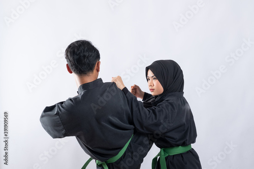 Two fighters in pencak silat Hitam uniform fight in a push against an isolated background
