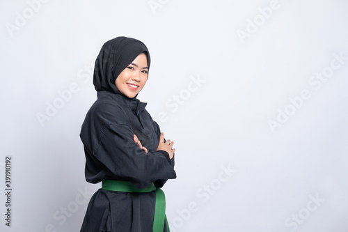 woman in hijab in pencak silat uniform poses crossed hands with copyspace in isolated background photo