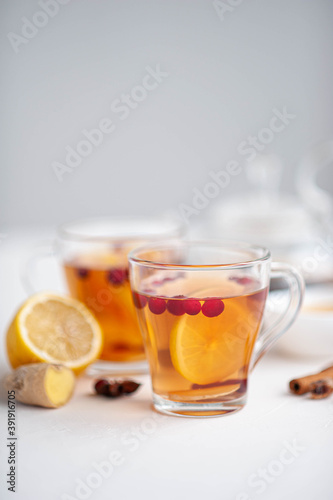 Winter hot tea to strengthen the immune system. Two glass cups in which pour hot tea from the kettle on a white background. Selective focus.