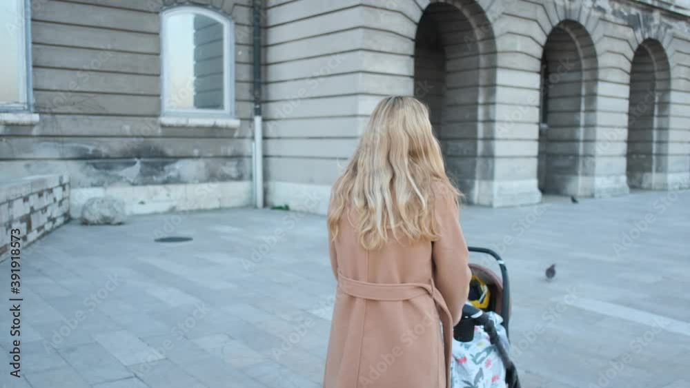 blonde woman walking with a stroller with a baby blonde woman walking with a stroller with a baby