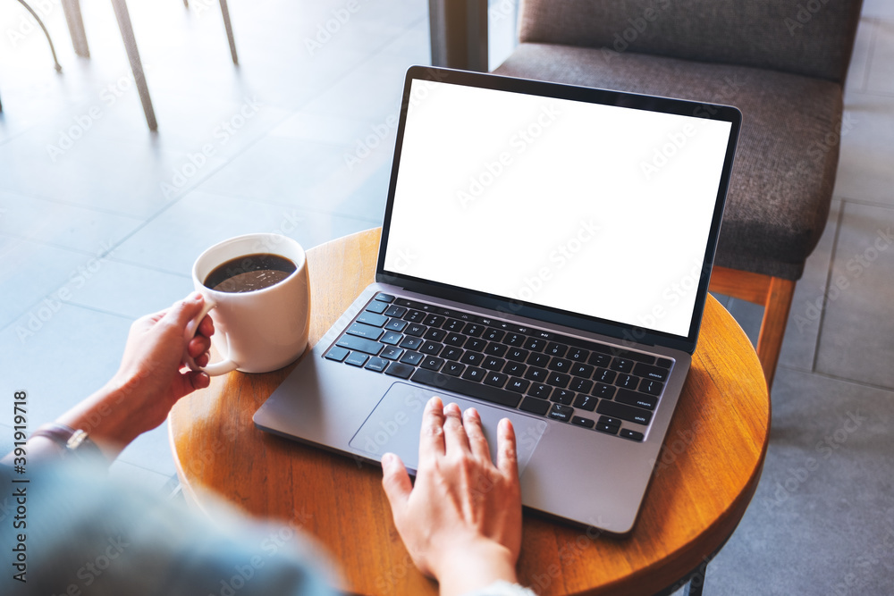 Mockup image of a hand touching on laptop computer touchpad with blank white desktop screen while drinking coffee Mockup image of a hand touching on laptop computer touchpad with blank white desktop screen while drinking coffee