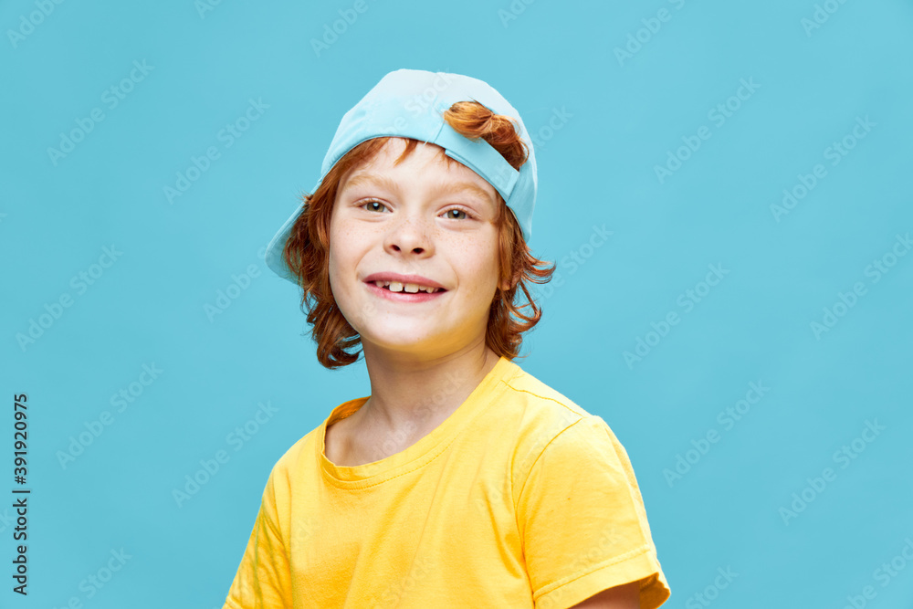 Cheerful red-haired child blue cap on his head close-up fun yellow t-shirt Cheerful red-haired child blue cap on his head close-up fun yellow t-shirt