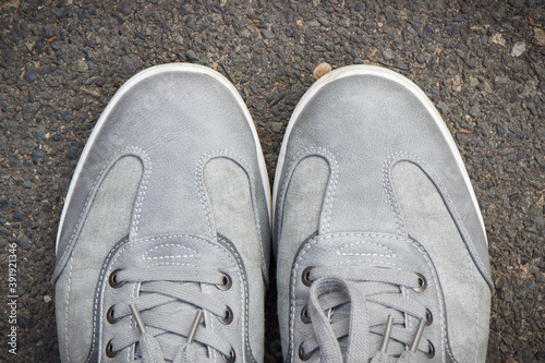 Gray leather shoes on asphalt road or footpath. Male footwear