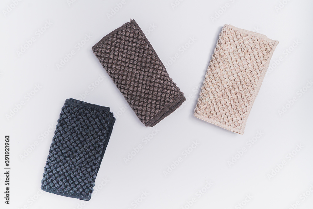 3 small kitchen towels, with recycled material in light brown, dark brown, and dark blue color. On the white background surface 3 small kitchen towels, with recycled material in light brown, dark brown, and dark blue color. On the white background surface