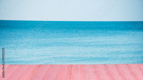 Pink wooden floor of swimming pool with sky and sea