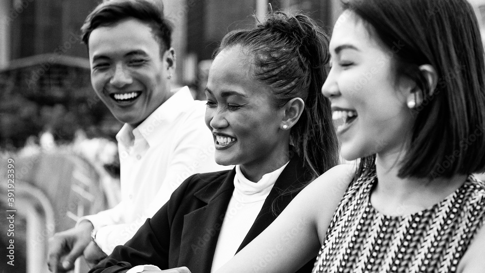 Three asian young friends standing outdoor in the city talking, smiling  and enjoying city life