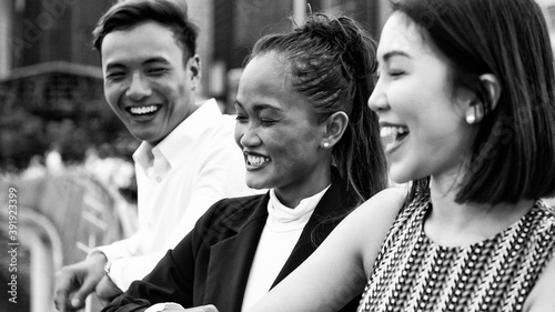Three asian young friends standing outdoor in the city talking, smiling and enjoying city life