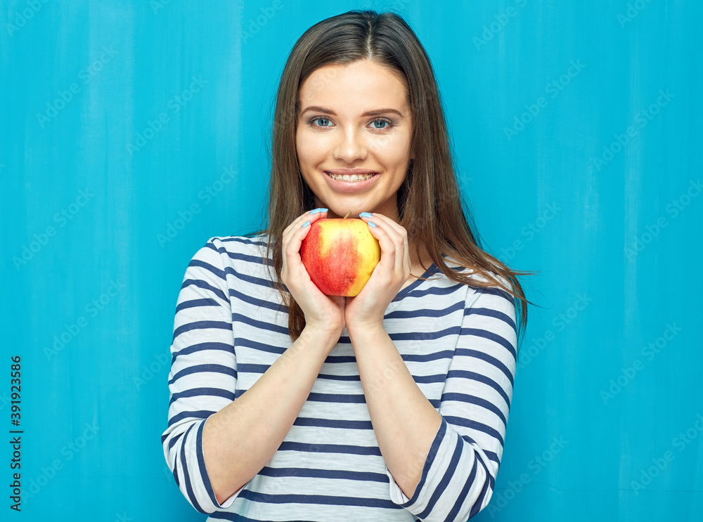 Smiling young woman with dental braces holding red apple. Smiling young woman with dental braces holding red apple.