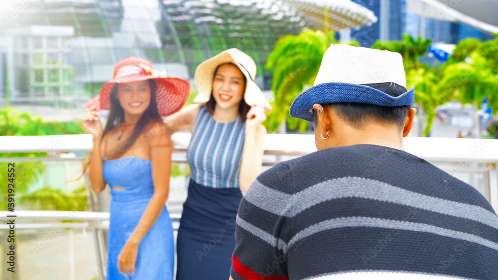Naklejka premium Three asian young friends enjoy outdoor time taking pictures along the city streets