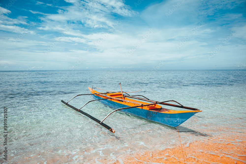 Traditional Filipino boat on a white beach in the sea