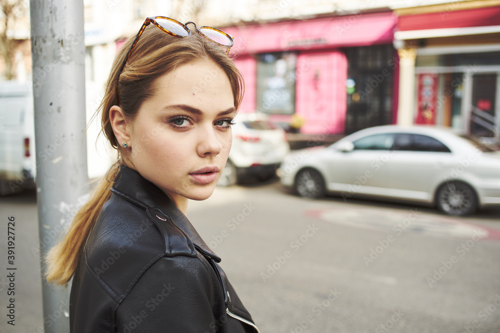 woman at a stop on the street and parked cars in the background woman at a stop on the street and parked cars in the background