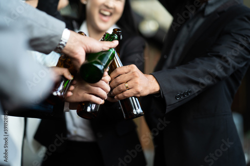 Group of friends Hands Hold Beverage Beers Bottle and toasting in the club. Celebration, Party People Christmas and Happy new year concept. Asian business people in party.