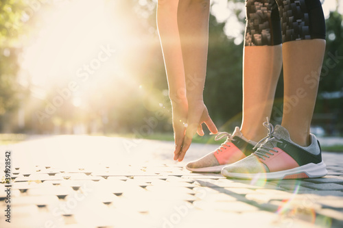 Woman stretching before morning run in park, closeup. Space for text