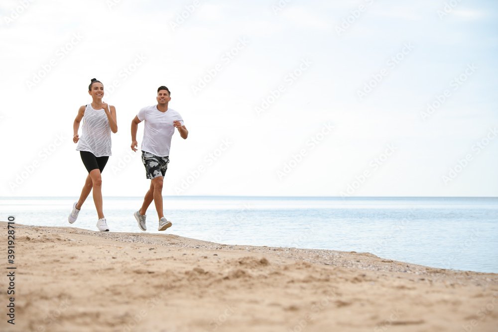 Couple running together on beach, space for text. Body training Couple running together on beach, space for text. Body training