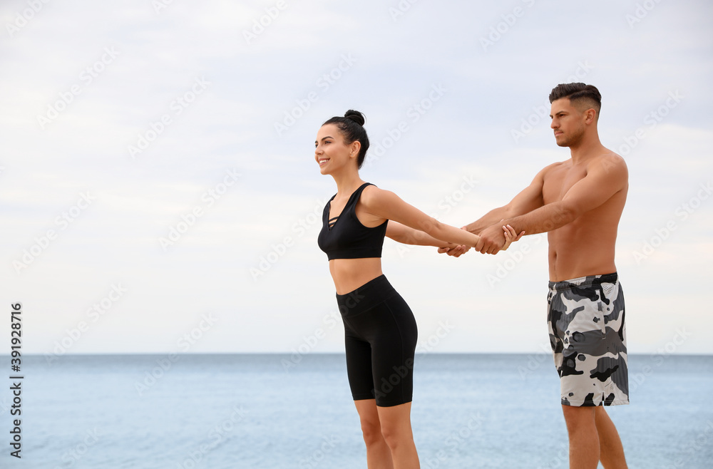 Couple doing exercise together on beach, space for text. Body training Couple doing exercise together on beach, space for text. Body training