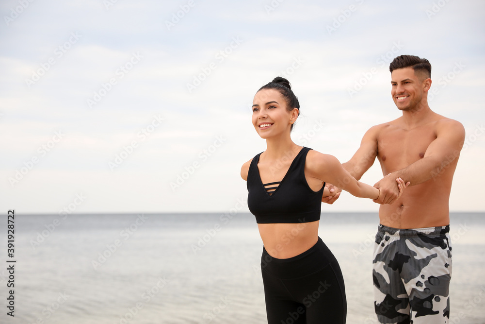 Couple doing exercise together on beach, space for text. Body training Couple doing exercise together on beach, space for text. Body training