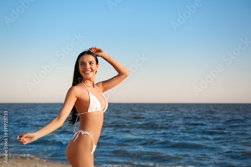 Beautiful young woman in white stylish bikini on beach. Space for text © New Africa