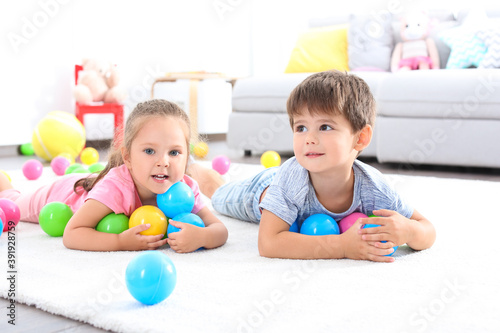 Cute little children playing with toys on floor at home
