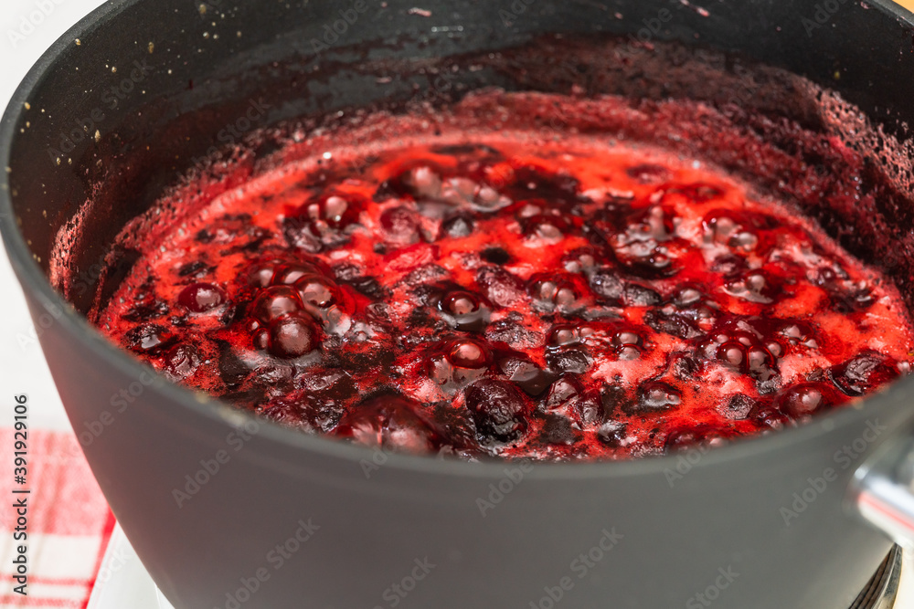 Cranberry sauce being heated up in a pan, close up view, selective focus. Cooking process, cranberry sauce recipe Cranberry sauce being heated up in a pan, close up view, selective focus. Cooking process, cranberry sauce recipe
