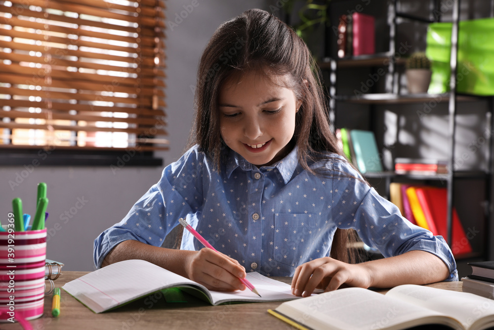 Pretty preteen girl doing homework at table Pretty preteen girl doing homework at table